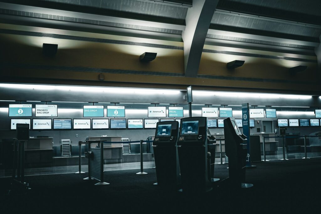 Leere Check-in-Schalter mit leuchtenden Bildschirmen am Flughafen, wo Fluggastrechte Verspätung oft beginnen